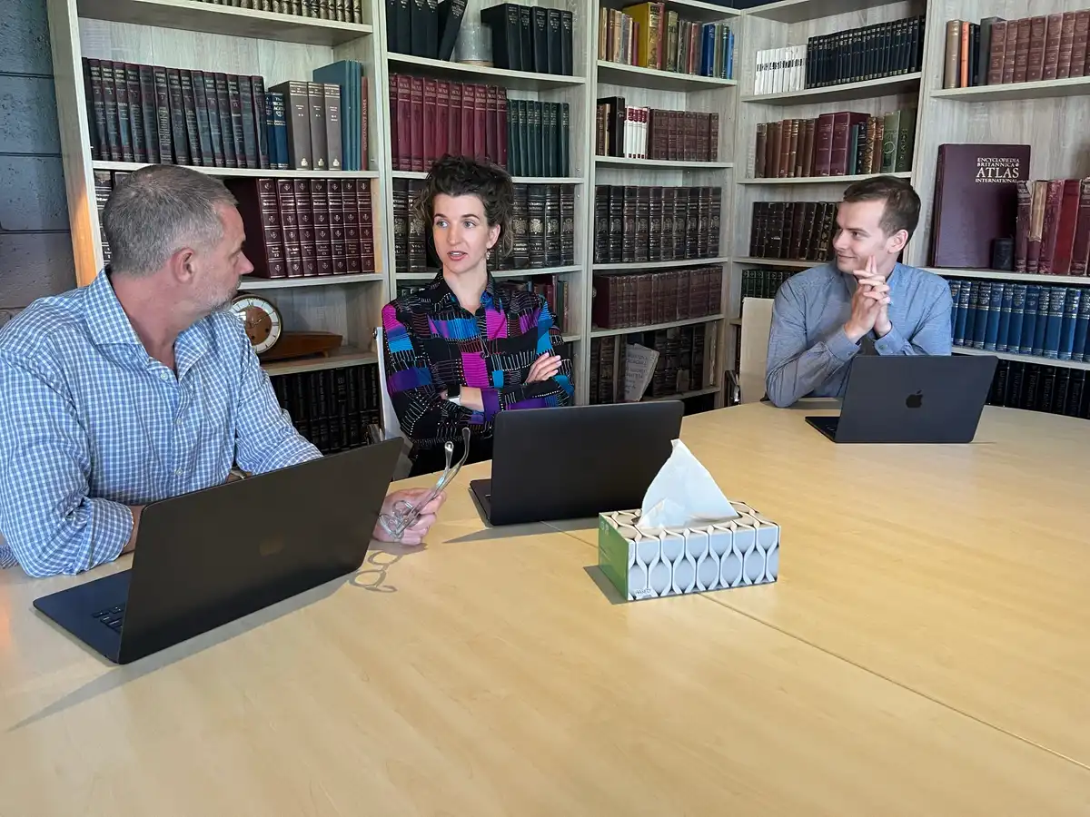 Mark Lucas, Eva Trebilco and Caleb Lucas working at a table with laptops