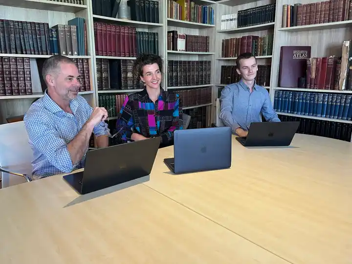 Mark Lucas explaining a point to Eva Trebilco and Caleb Lucas at a table